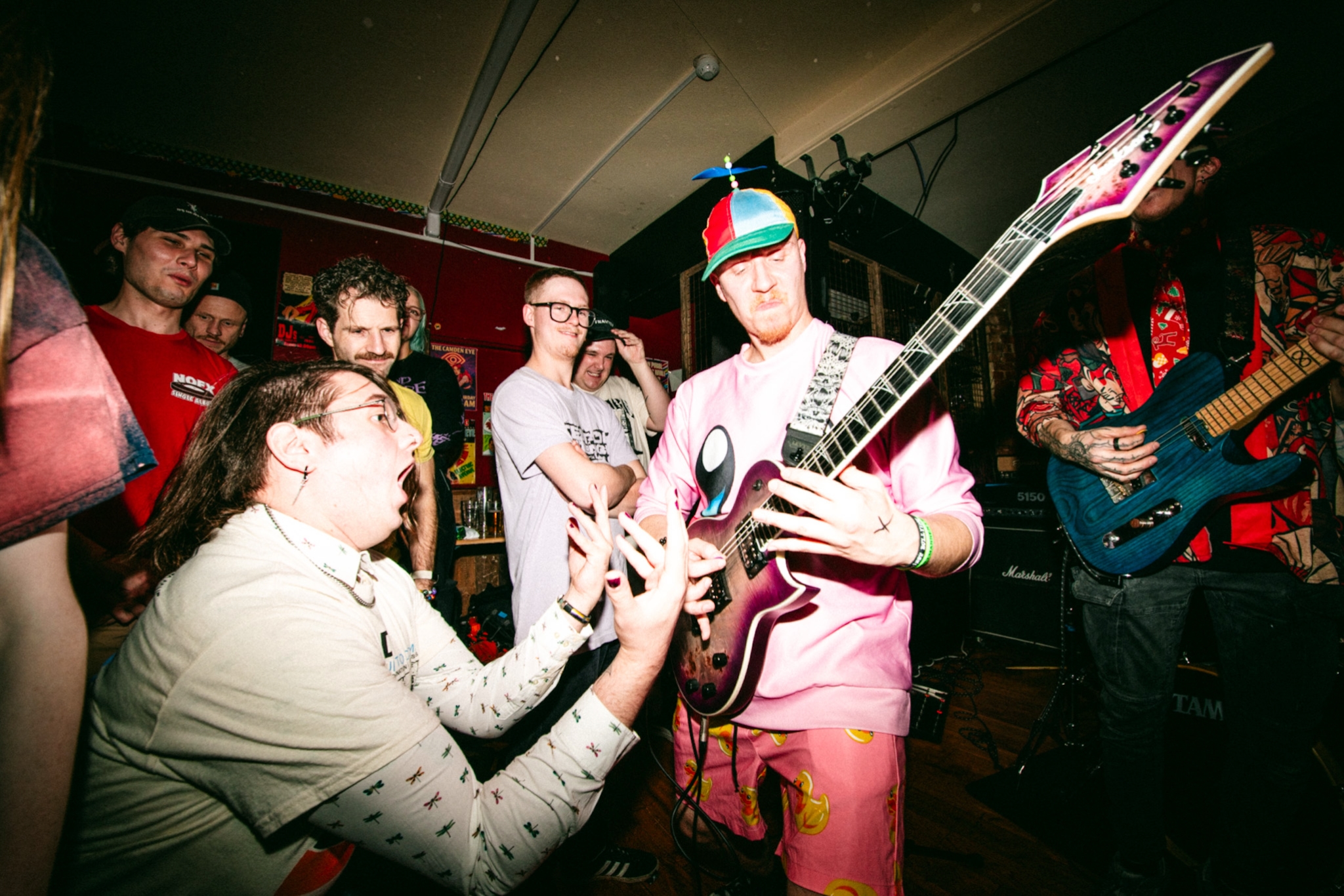 Photograph of a person playing a guitar whilst another person is in awe of their performance.